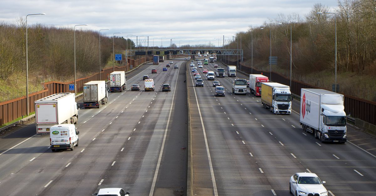 UK motorway with multiple lanes of cars, vans and lorries in daytime traffic.