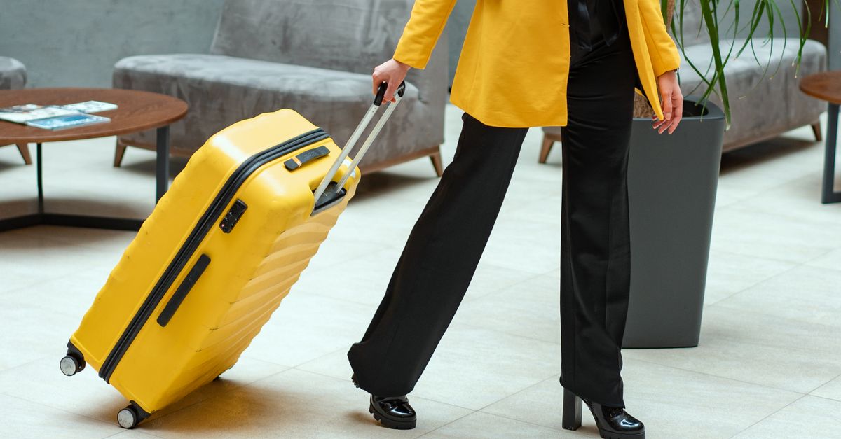 Traveller pulling a suitcase through a bright terminal-style hall.