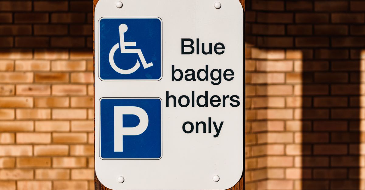 Blue Badge holders only parking sign with wheelchair symbol on a brick wall.