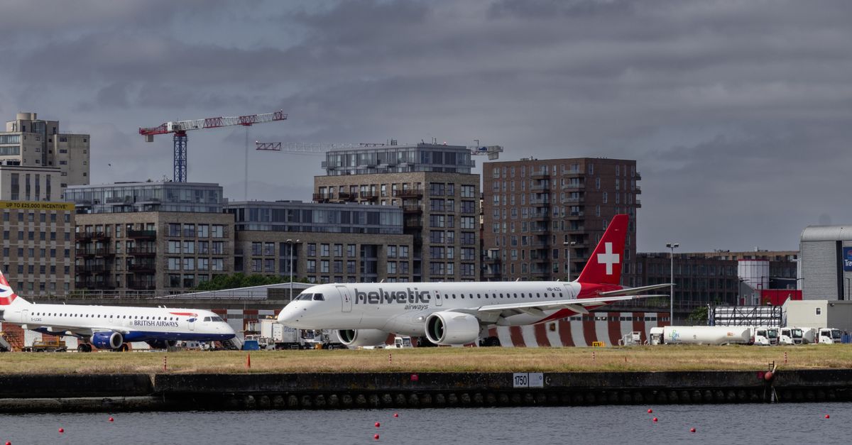 Aircraft on the apron at London City Airport with Docklands residential towers behind.