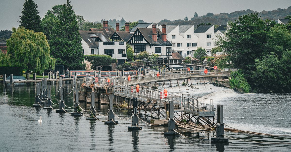 Thames-side scene with a weir, footbridge and riverside houses