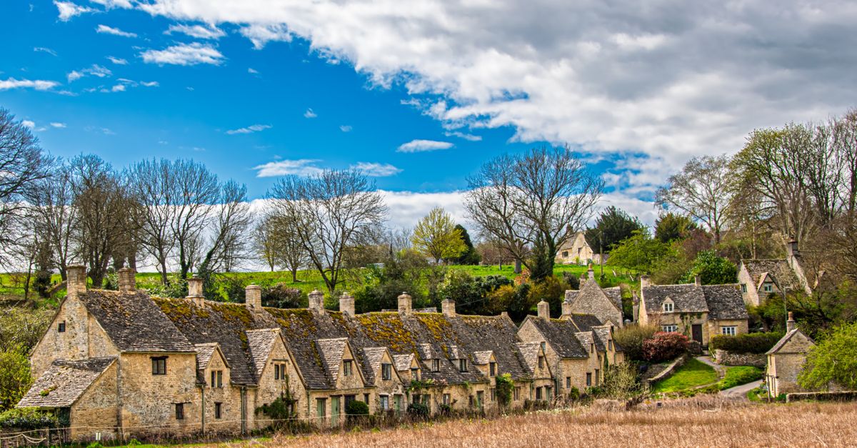 Picturesque Cotswold village with historic stone houses and vibrant spring scenery.