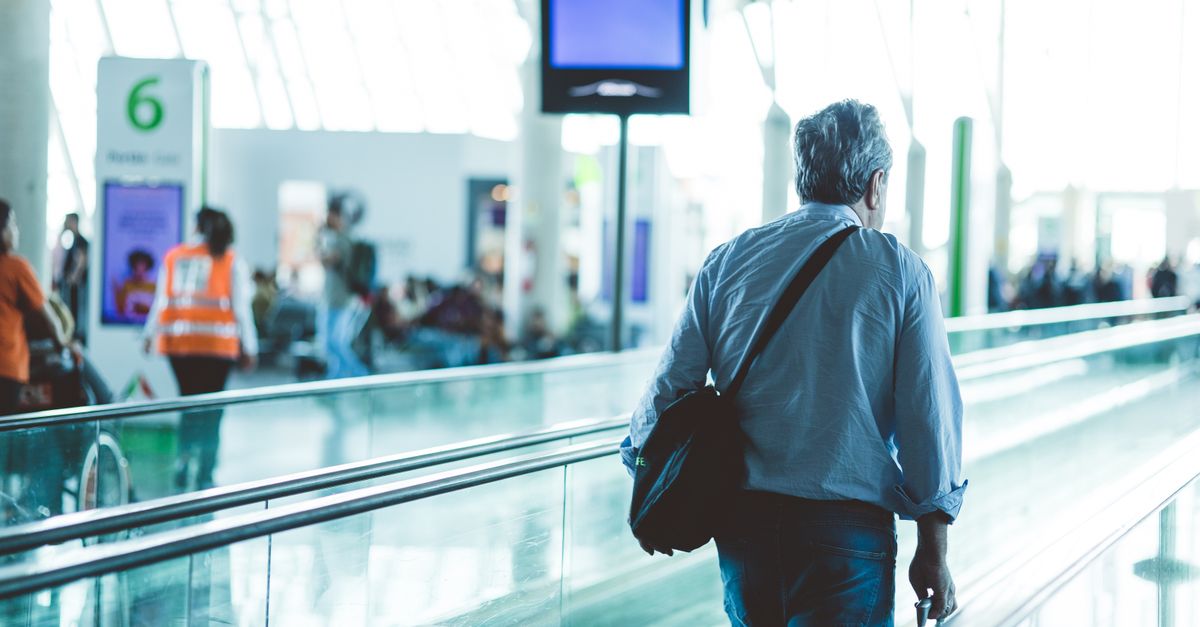 Traveller with a shoulder bag on an airport terminal moving walkway.