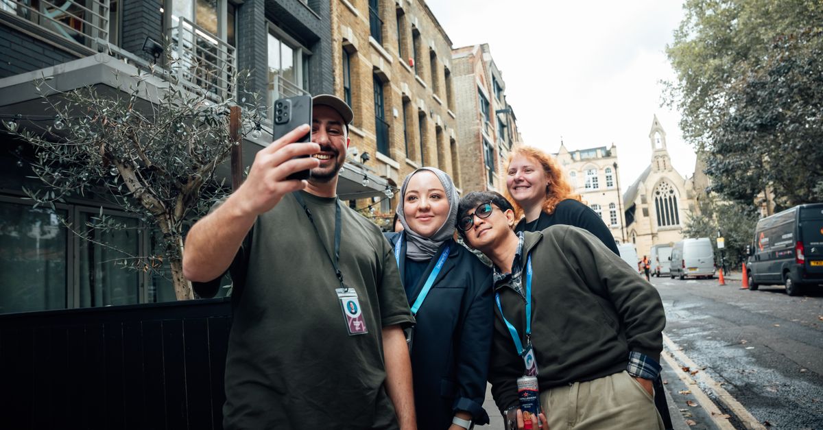 Group of friends taking a selfie on a lively street in London with a church in the background.